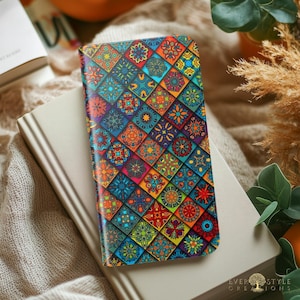 May include: A rectangular phone case featuring a vibrant, multi-colored mosaic pattern of repeating diamond-shaped tiles. Each tile displays intricate, symmetrical floral and geometric designs in shades of blue, orange, red, and yellow.