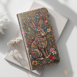 May include: A rectangular wallet featuring a vibrant, intricate illustration of a rabbit surrounded by colorful flowers, leaves, and butterflies. The design incorporates detailed patterns in shades of gold, red, blue, and green, with the text EVER STYLE CREATIONS in the bottom corner.