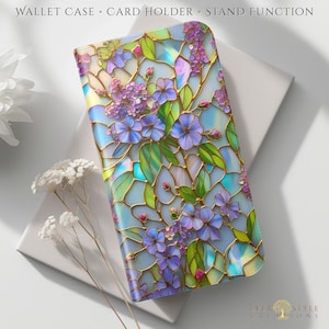 Puede incluir: Una funda de cartera con un diseño floral. La funda presenta un patrón de estilo vidriera con flores azules, moradas y verdes. La funda tiene las palabras "WALLET CASE • CARD HOLDER • STAND FUNCTION" impresas.