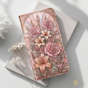 Pode incluir: Uma carteira retangular com um design floral rosa iridescente com rosas e lírios em relevo. A superfície tem um acabamento perolado com contornos em tom de cobre formando uma moldura arqueada. O texto Ever Style Creations está no canto inferior.