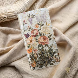Op de afbeelding: Een rechthoekig telefoonhoesje met een mozaïekontwerp van bloemen en bladeren in tinten crème, perzik, roze en groen. Het oppervlak bestaat uit kleine, parelmoerachtige stukjes die in een bloemmotief zijn gerangschikt met goudkleurige accenten.