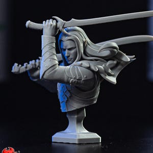 Puede incluir: Busto gris de un guerrero de fantasía con pelo largo, sosteniendo dos espadas en una pose dinámica. La figura está vestida con una armadura detallada, con una expresión severa. El busto está montado sobre una base cuadrada.