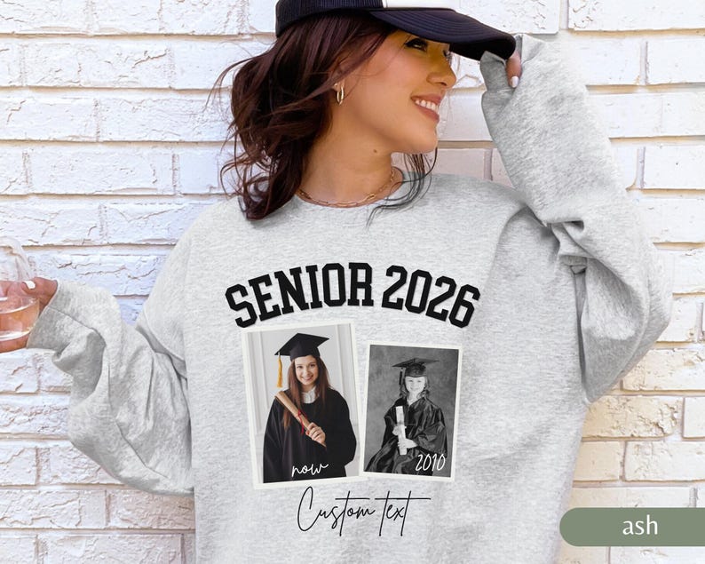 May include: Ash gray sweatshirt with the text "SENIOR 2026" in black block letters. Two framed photos of a graduate are below the text. The words "now" and "2010" are below the photos. The words "Custom Text" are written in cursive.
