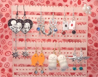 Choose from 6 Unique Earring Pairs: Dead Lovers, Celestial Key, Asymmetrical Aces, Goldfish, Fuzzy Otters, and Sharkbite.