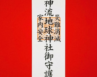 Op de afbeelding: Een witte, rechthoekige Japanse Omamori-hanger met zwarte kalligrafie en een tarwe-ontwerp bovenaan. De hanger heeft twee gestileerde vossenillustraties aan de onderkant, tegen een felrode achtergrond.