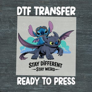 May include: DTF transfer featuring Stitch from Lilo & Stitch and Toothless from How to Train Your Dragon. The image includes the text "STAY DIFFERENT - STAY WEIRD" and "READY TO PRESS". The characters are set against a light blue and gray background.