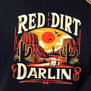 May include: Black cropped sweatshirt with a graphic print of a desert landscape with a red sunset, cacti, and the text "RED DIRT DARLIN'" in yellow and white.
