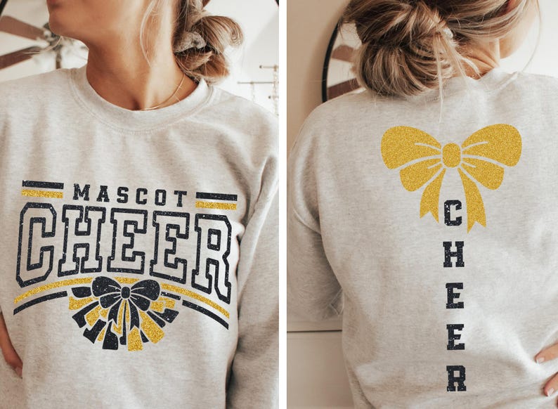 Puede incluir: Una sudadera gris con las palabras "MASCOT CHEER" en negro con un lazo de purpurina dorada en la parte delantera. La parte posterior de la sudadera tiene un lazo de purpurina dorada y la palabra "CHEER" verticalmente en negro.