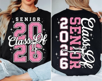 May include: Black sweatshirt featuring the text "SENIOR 2026 Class Of" in white and pink glitter lettering on the front. The back of the sweatshirt has the same text in a vertical layout. The design includes a bow graphic.