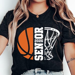 May include: Black t-shirt with a white basketball and basketball hoop graphic. The text "Senior 2026" is printed on the shirt.