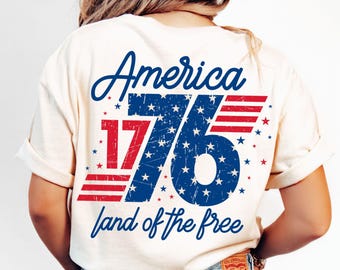 May include: A white t-shirt with a distressed blue and red graphic that says "America 1776 land of the free".