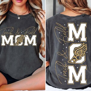 May include: A dark gray t-shirt with gold glitter lettering that reads "Track & Field MOM" with a gold glitter running shoe graphic. The back of the shirt has the same design but vertically with the text reading "Track & Field MOM"