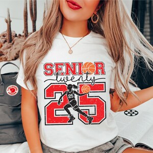 May include: White t-shirt with a red and black graphic design that says "Senior twenty five" with a basketball player silhouette and a basketball.