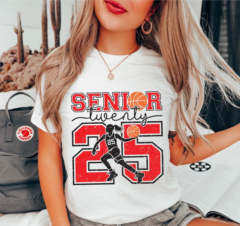 May include: White t-shirt with a red and black graphic design that says "Senior twenty five" with a basketball player silhouette and a basketball.