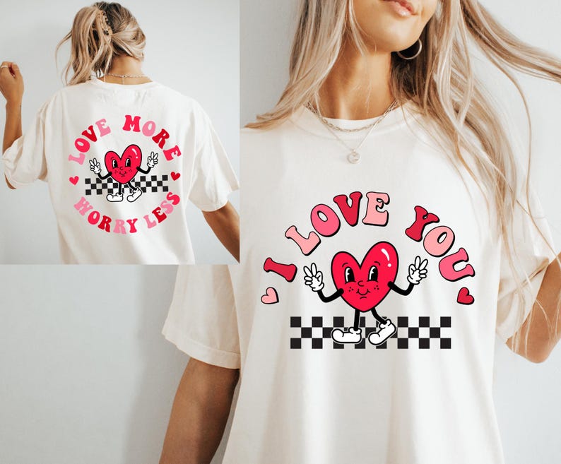 May include: Cream-colored t-shirt featuring a retro design with a red heart character giving peace signs. The words "I LOVE YOU" are arched above the heart. A matching design is on the back, with the words "LOVE MORE WORRY LESS".