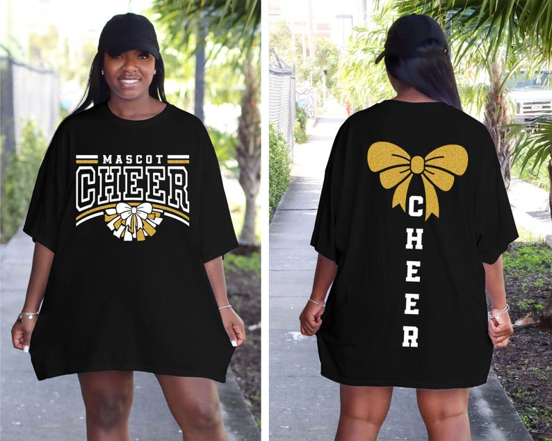 Puede incluir: Camiseta negra de gran tama&ntilde;o con letras doradas de purpurina que dicen "Mascot Cheer" en la parte delantera y "Cheer" verticalmente con un lazo dorado de purpurina en la parte posterior.