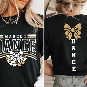 May include: Black t-shirt with gold glitter text and a gold glitter bow. The text on the front says "Mascot Dance" and the text on the back says "Dance".