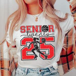 May include: White t-shirt with red and black text that says "Senior twenty five" with a basketball player graphic.