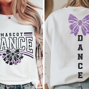 May include: White t-shirt with a purple glitter bow and the text "Mascot Dance" on the front. The back of the shirt has a purple glitter bow and the text "Dance" vertically down the back.