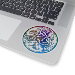 May include: A circular sticker with a rainbow gradient background featuring a Celtic knot design of two intertwined dogs. The dogs are white and the design is in a circular pattern.