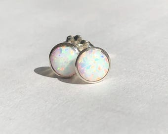 May include: A pair of silver stud earrings with white opal stones.
