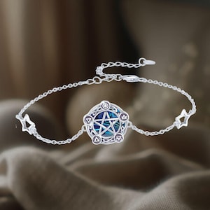 May include: A silver bracelet with a blue and green abalone shell pentagram charm surrounded by five silver symbols. The bracelet has a silver chain with two star-shaped charms.
