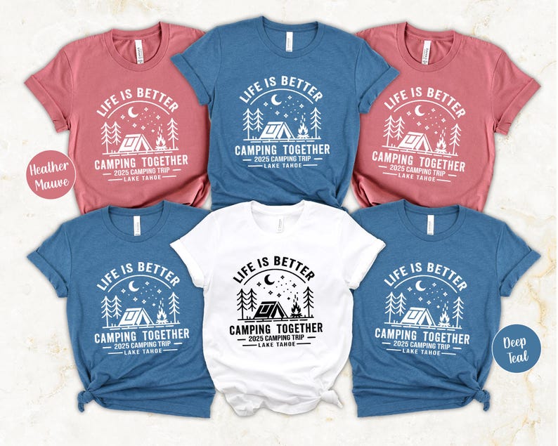 May include: A collection of short-sleeved t-shirts in various colors, including heather mauve, deep teal, and white. Each shirt features a camping-themed graphic with the text "LIFE IS BETTER CAMPING TOGETHER 2025 CAMPING TRIP LAKE TAHOE."
