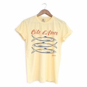 Butter Yellow T-shirt with the text Côtes d'Azur, France.

Côtes d'Azur France T-Shirt, Old Money Aesthetic, 3 Fish , French Riviera, Heritage, Sardines TShirt, France Travel Tee, Coastal Aesthetic, Retro Graphic Tee, French Vacation, Mediterranean