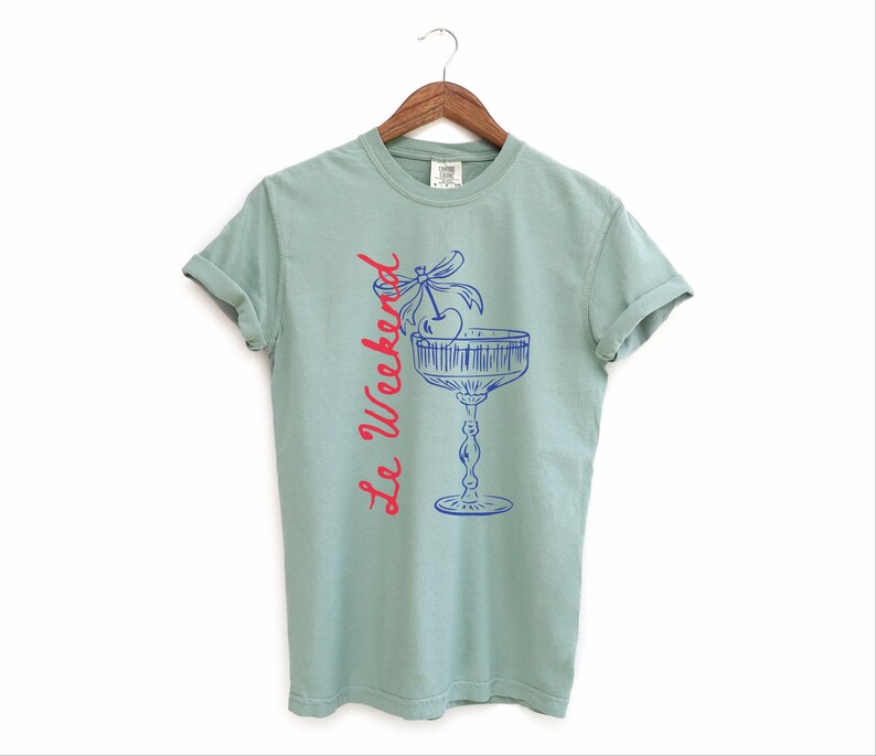 Bay Green T-shirt with the text Le Weekend and a Cherry Coquette Cocktail graphic.

Because what’s a good time without a little flair?

Perfect for brunch dates, rooftop soirées, or just channeling that effortlessly flirty energy. French twist, retro feel, full-on main character mood.
Weekend Shirt, Le Weekend, French T-Shirt, Weekending, Vintage Aesthetic, Coquette Bow Cherry, Cocktail Tee, y2k T-shirt, weekend vibes tee.