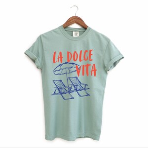 Bay Green Tee with the text LA DOLCE VITA across the chest.
Two sun chairs. One umbrella. Zero worries. Italy -where the espresso hits hard, the gelato never melts, and responsibility? Never heard of her.
Endless summer, featuring a dreamy graphic of striped beach bliss. Perfect for sun-chasers, rule-breakers, and anyone who believes naps are a lifestyle.
La Dolce Vita shirt, Tomato Girl summer, Limoncello, spaghetti vibes. Retro foodie, Portofino, Amalfi Coast Shirt, Sardines Tee