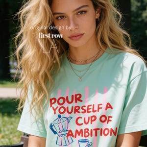 Woman wearing Dolly Parton "Pour Yourself a Cup of Ambition" Shirt, Retro Coffee Graphic, 9 to 5 Country Music Tee, Moka Pot, Coffee Club, Caffeine Lover.

Original desgin and copyright by first row LA.