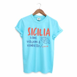 Lagoon Blue T-shirt with the text Sicilia, Vino, Volcano and Vendetta, La Dolce Vita. 

A wearable love letter to the drama, beauty, and indulgence of Sicilian culture.

Great for wine lovers, pasta enthusiasts, spontaneous adventurers, and anyone who knows that revenge is a dish best served... with a glass of Nero d’Avola.
Wear it to your next pizza night, wine tasting, or while planning your escape to the Amalfi Coast.