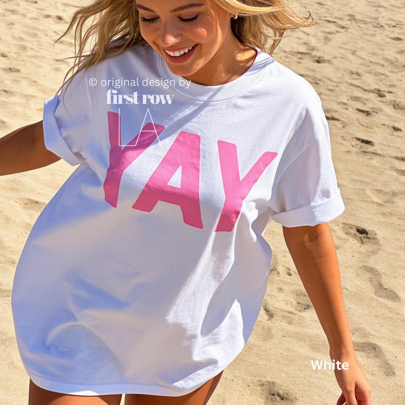 Woman wearing YAY T-Shirt, Happy Pink Graphic Tee, Cute Positive Shirt, Feel Good Tee, Fun Handwritten Statement Shirt, Dopamine shirt.

Original design and copyright by first row LA 2026.