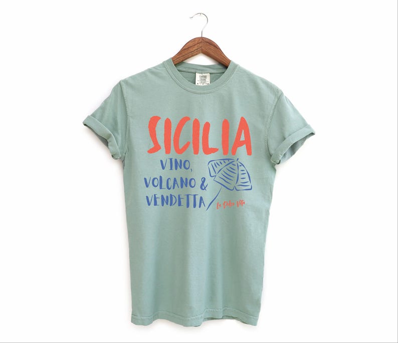 Bay Green. T-shirt with the text Sicilia, Vino, Volcano and Vendetta, La Dolce Vita. 

A wearable love letter to the drama, beauty, and indulgence of Sicilian culture.

Great for wine lovers, pasta enthusiasts, spontaneous adventurers, and anyone who knows that revenge is a dish best served... with a glass of Nero d’Avola.
Wear it to your next pizza night, wine tasting, or while planning your escape to the Amalfi Coast.