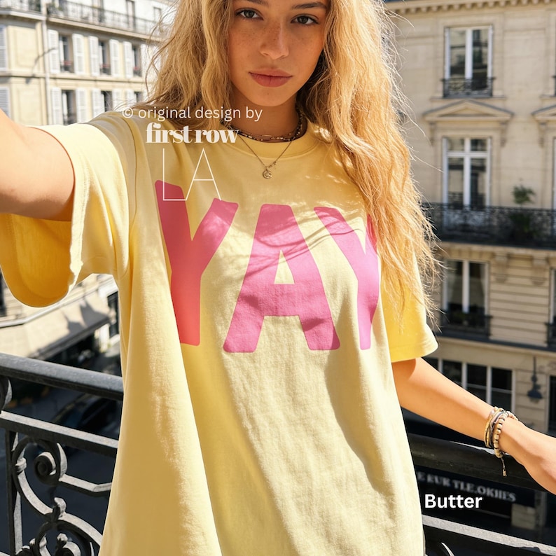 Woman wearing YAY T-Shirt, Happy Pink Graphic Tee, Cute Positive Shirt, Feel Good Tee, Fun Handwritten Statement Shirt, Dopamine shirt.

Original design and copyright by first row LA 2026.