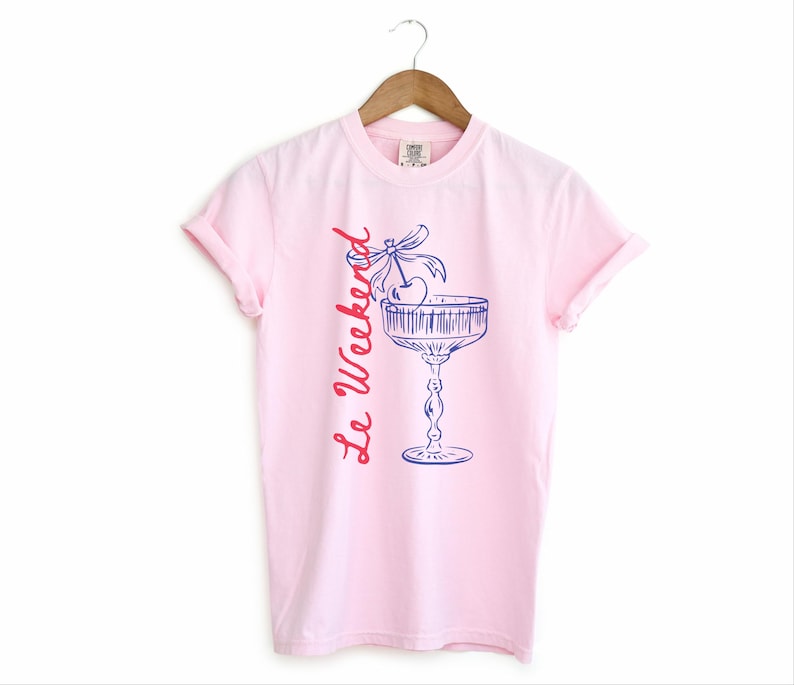 Blossom Pink T-shirt with the text Le Weekend and a Cherry Coquette Cocktail graphic.

Because what’s a good time without a little flair?

Perfect for brunch dates, rooftop soirées, or just channeling that effortlessly flirty energy. French twist, retro feel, full-on main character mood.
Weekend Shirt, Le Weekend, French T-Shirt, Weekending, Vintage Aesthetic, Coquette Bow Cherry, Cocktail Tee, y2k T-shirt, weekend vibes tee.
