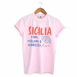 Blossom Light Pink T-shirt with the text Sicilia, Vino, Volcano and Vendetta, La Dolce Vita. 

A wearable love letter to the drama, beauty, and indulgence of Sicilian culture.

Great for wine lovers, pasta enthusiasts, spontaneous adventurers, and anyone who knows that revenge is a dish best served... with a glass of Nero d’Avola.
Wear it to your next pizza night, wine tasting, or while planning your escape to the Amalfi Coast.