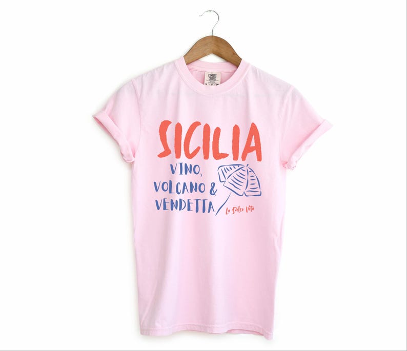 Blossom Light Pink T-shirt with the text Sicilia, Vino, Volcano and Vendetta, La Dolce Vita. 

A wearable love letter to the drama, beauty, and indulgence of Sicilian culture.

Great for wine lovers, pasta enthusiasts, spontaneous adventurers, and anyone who knows that revenge is a dish best served... with a glass of Nero d’Avola.
Wear it to your next pizza night, wine tasting, or while planning your escape to the Amalfi Coast.