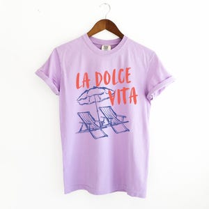 Orchid Purple Tee with the text LA DOLCE VITA across the chest.
Two sun chairs. One umbrella. Zero worries. Italy -where the espresso hits hard, the gelato never melts, and responsibility? Never heard of her.
Endless summer, featuring a dreamy graphic of striped beach bliss. Perfect for sun-chasers, rule-breakers, and anyone who believes naps are a lifestyle.
La Dolce Vita shirt, Tomato Girl summer, Limoncello, spaghetti vibes. Retro foodie, Portofino, Amalfi Coast Shirt, Sardines Tee