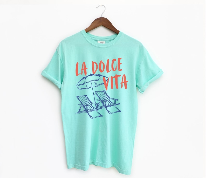 Island Reef Tee with the text LA DOLCE VITA across the chest.
Two sun chairs. One umbrella. Zero worries. Italy -where the espresso hits hard, the gelato never melts, and responsibility? Never heard of her.
Endless summer, featuring a dreamy graphic of striped beach bliss. Perfect for sun-chasers, rule-breakers, and anyone who believes naps are a lifestyle.
La Dolce Vita shirt, Tomato Girl summer, Limoncello, spaghetti vibes. Retro foodie, Portofino, Amalfi Coast Shirt, Sardines Tee