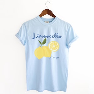 Chambray Light Blue T-shirt with the text Limoncello, La Dolce Vita, follewed by a juicy lemon graphics.
Limoncello Shirt, La Dolce Vita Tee, Lemon Shirt, Amalfi Coast, Italy TShirt, Vacay T-Shirt, Lemons Tee, Cocktail T Shirt, Retro Graphic Tee