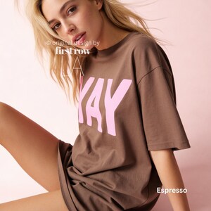 Woman wearing YAY T-Shirt, Happy Pink Graphic Tee, Cute Positive Shirt, Feel Good Tee, Fun Handwritten Statement Shirt, Dopamine shirt.

Original design and copyright by first row LA 2026.