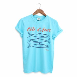 Lagoon Blue T-shirt with the text Côtes d'Azur, France.

Côtes d'Azur France T-Shirt, Old Money Aesthetic, 3 Fish , French Riviera, Heritage, Sardines TShirt, France Travel Tee, Coastal Aesthetic, Retro Graphic Tee, French Vacation, Mediterranean