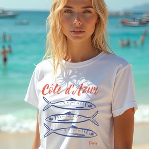 Model in Southern France wearing a white T-shirt with the text Côtes d'Azur, France.

Côtes d'Azur France T-Shirt, Old Money Aesthetic, 3 Fish , French Riviera, Heritage, Sardines TShirt, France Travel Tee, Coastal Aesthetic, Retro Graphic Tee, French Vacation, Mediterranean