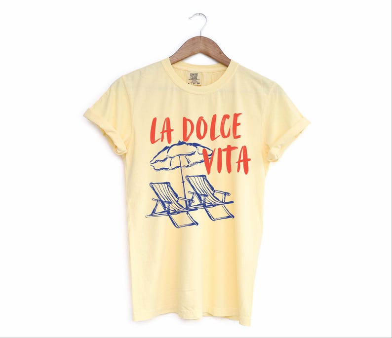 Butter Yellow Tee with the text LA DOLCE VITA across the chest.
Two sun chairs. One umbrella. Zero worries. Italy -where the espresso hits hard, the gelato never melts, and responsibility? Never heard of her.
Endless summer, featuring a dreamy graphic of striped beach bliss. Perfect for sun-chasers, rule-breakers, and anyone who believes naps are a lifestyle.
La Dolce Vita shirt, Tomato Girl summer, Limoncello, spaghetti vibes. Retro foodie, Portofino, Amalfi Coast Shirt, Sardines Tee