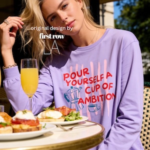 Woman wearing Dolly Parton Pour Yourself a Cup of Ambition Shirt, Retro Coffee T, 9 to 5 Country Music Tee, Moka Pot, Coffee Club, Long Sleeve T-Shirt.

Original design and copyright by first row LA 2025.