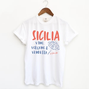 White T-shirt with the text Sicilia, Vino, Volcano and Vendetta, La Dolce Vita. 

A wearable love letter to the drama, beauty, and indulgence of Sicilian culture.

Great for wine lovers, pasta enthusiasts, spontaneous adventurers, and anyone who knows that revenge is a dish best served... with a glass of Nero d’Avola.
Wear it to your next pizza night, wine tasting, or while planning your escape to the Amalfi Coast.