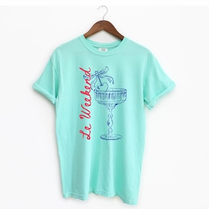 Island Reef T-shirt with the text Le Weekend and a Cherry Coquette Cocktail graphic.

Because what’s a good time without a little flair?

Perfect for brunch dates, rooftop soirées, or just channeling that effortlessly flirty energy. French twist, retro feel, full-on main character mood.
Weekend Shirt, Le Weekend, French T-Shirt, Weekending, Vintage Aesthetic, Coquette Bow Cherry, Cocktail Tee, y2k T-shirt, weekend vibes tee.