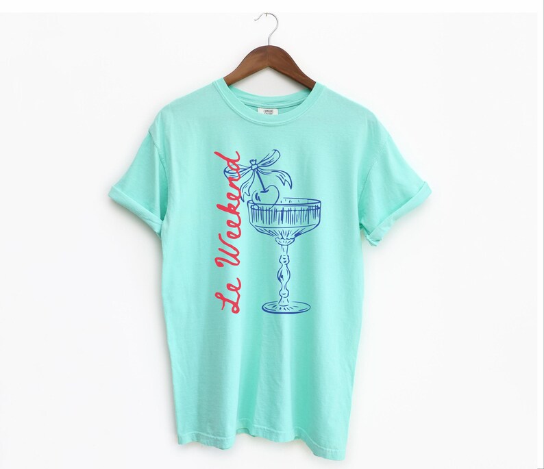 Island Reef T-shirt with the text Le Weekend and a Cherry Coquette Cocktail graphic.

Because what’s a good time without a little flair?

Perfect for brunch dates, rooftop soirées, or just channeling that effortlessly flirty energy. French twist, retro feel, full-on main character mood.
Weekend Shirt, Le Weekend, French T-Shirt, Weekending, Vintage Aesthetic, Coquette Bow Cherry, Cocktail Tee, y2k T-shirt, weekend vibes tee.
