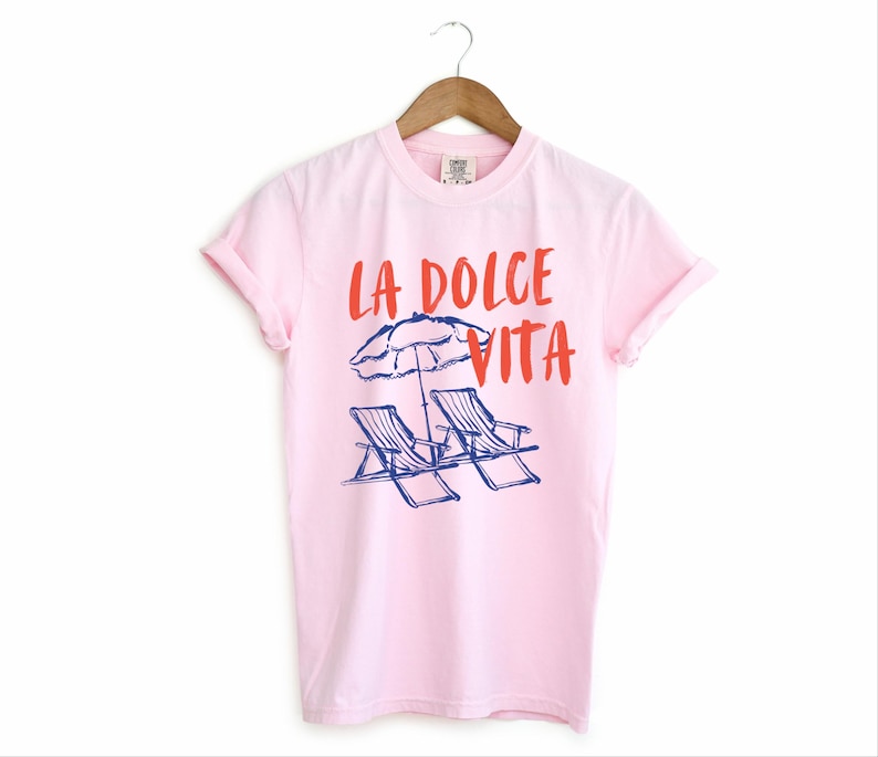 Blossom Light Pink Tee with the text LA DOLCE VITA across the chest.
Two sun chairs. One umbrella. Zero worries. Italy -where the espresso hits hard, the gelato never melts, and responsibility? Never heard of her.
Endless summer, featuring a dreamy graphic of striped beach bliss. Perfect for sun-chasers, rule-breakers, and anyone who believes naps are a lifestyle.
La Dolce Vita shirt, Tomato Girl summer, Limoncello, spaghetti vibes. Retro foodie, Portofino, Amalfi Coast Shirt, Sardines Tee